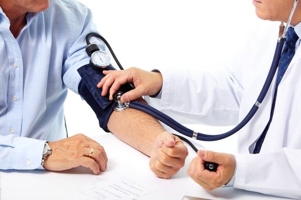 A primary care physician measures a patient's blood pressure during a routine office visit as part of a preventive health exam.
