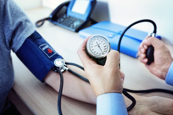 A healthcare provider measures a patient's blood pressure using a manual blood pressure cuff during a routine primary care appointment.